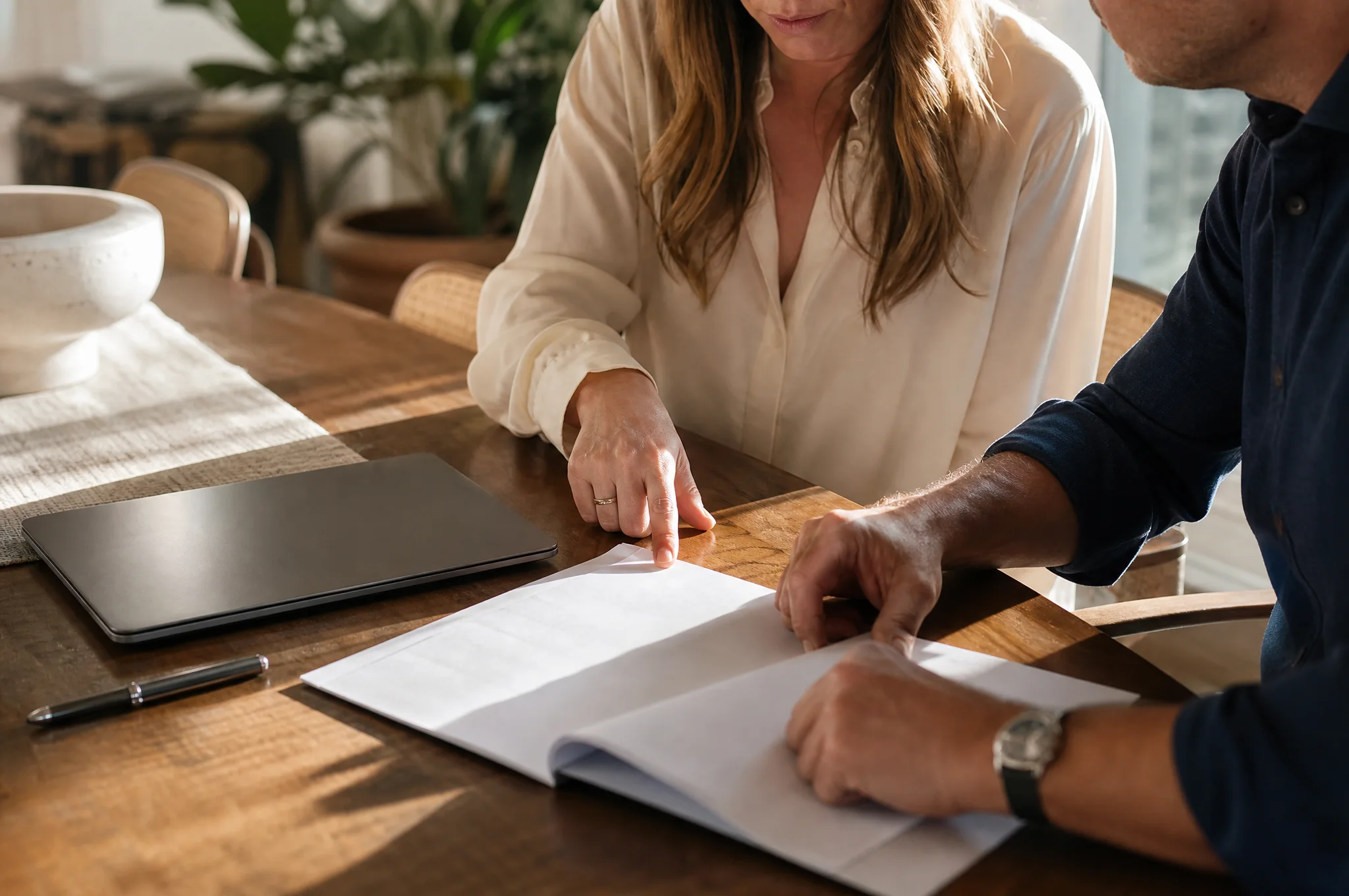 Homebuyers discussing offer terms over documents at a dining table